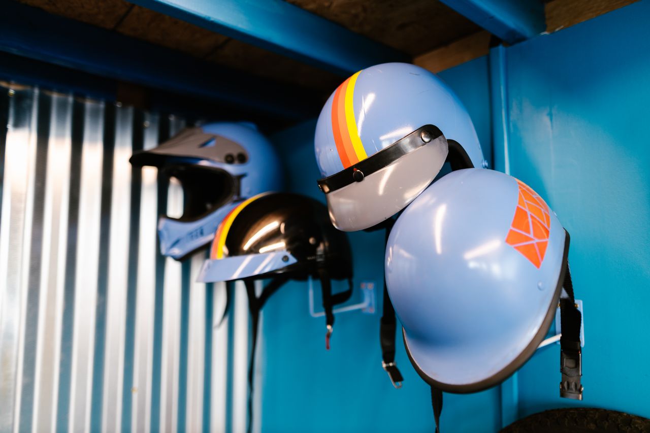services-09 Decorative retro helmets hanging on a blue interior wall, showcasing vintage style.