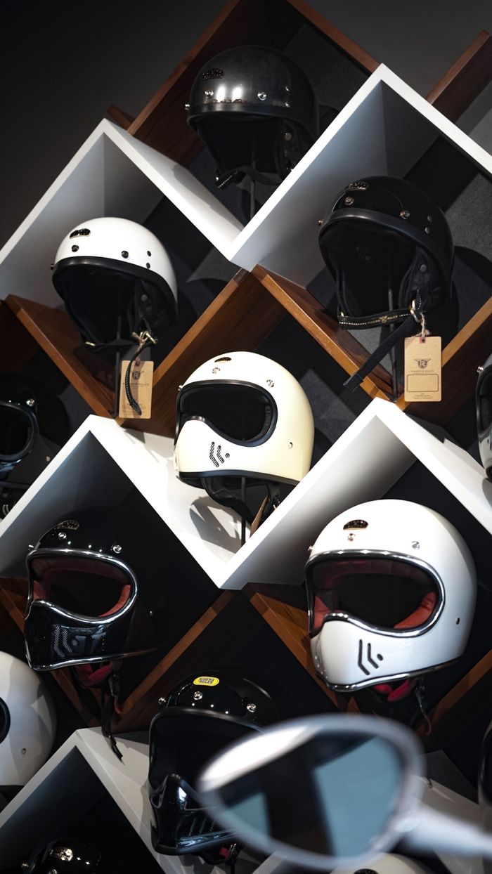 about-01 A variety of motorcycle helmets in different colors and styles displayed on a wooden shelf.