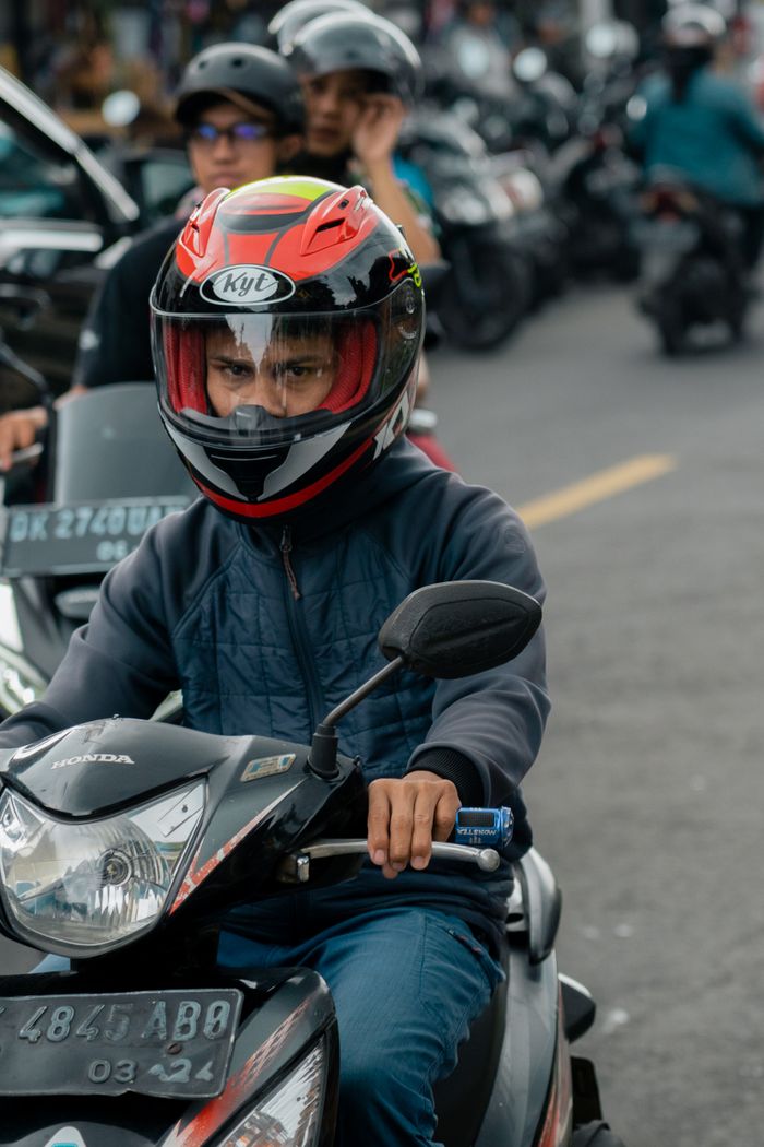 why-choose-us-03 Motorcyclist wearing helmet riding through traffic on a busy street during the day.