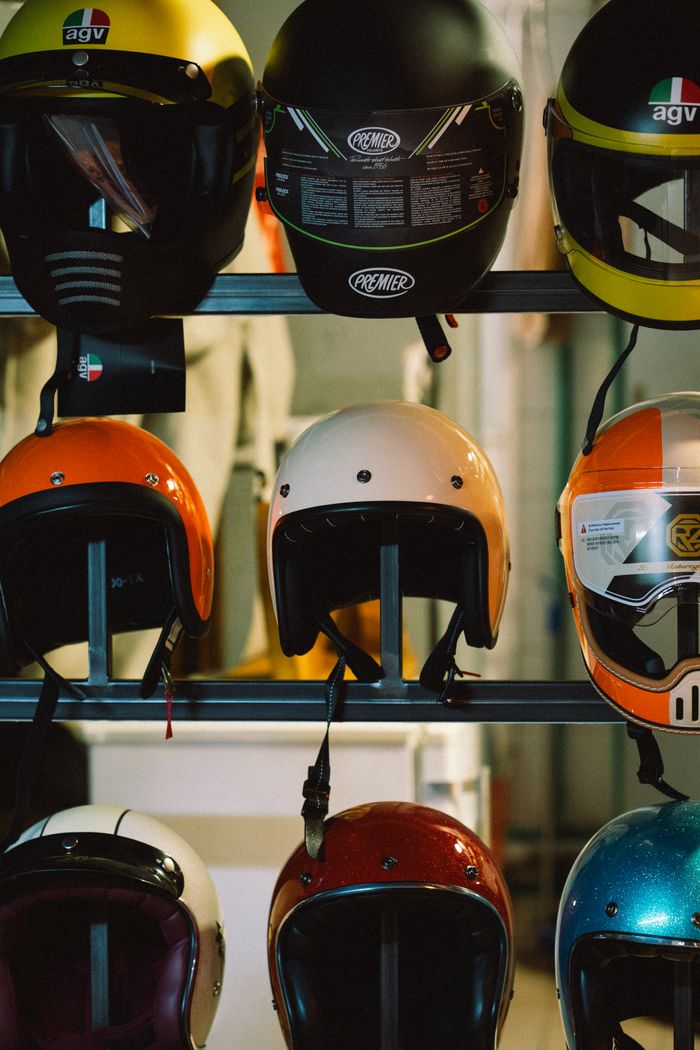 services-01 Variety of colorful motorcycle helmets displayed on a rack indoor.