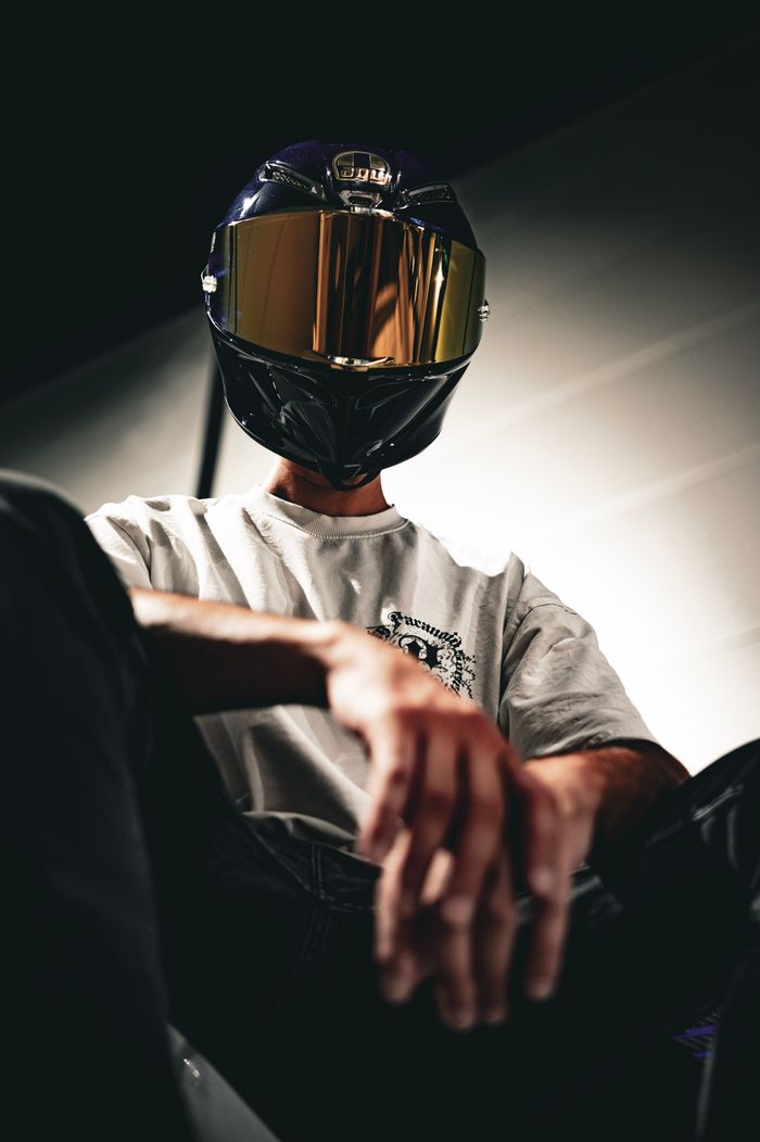 services-09 Low-angle shot of a motorcyclist in a helmet and casual attire, indoors.
