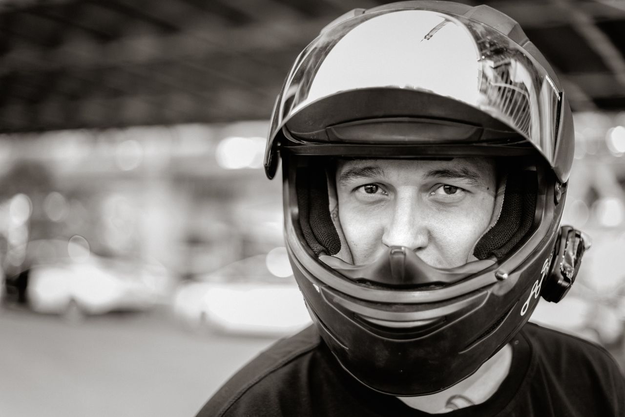 services-05 Monochrome close-up of a man wearing a helmet, offering a focused and intense expression.